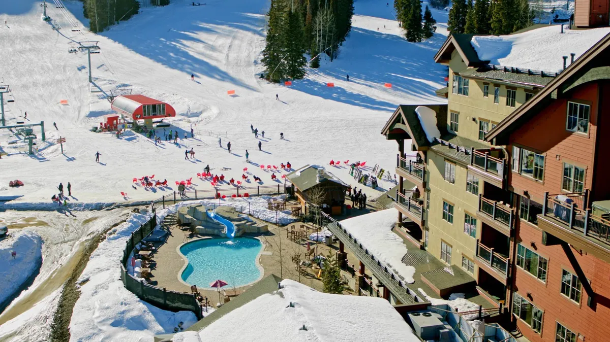 A vibrant exterior view showing ski slopes, a pool area, a ski lift, and the lodge's exterior. People are enjoying both winter sports and relaxing by the pool, capturing the festive energy of the resort.